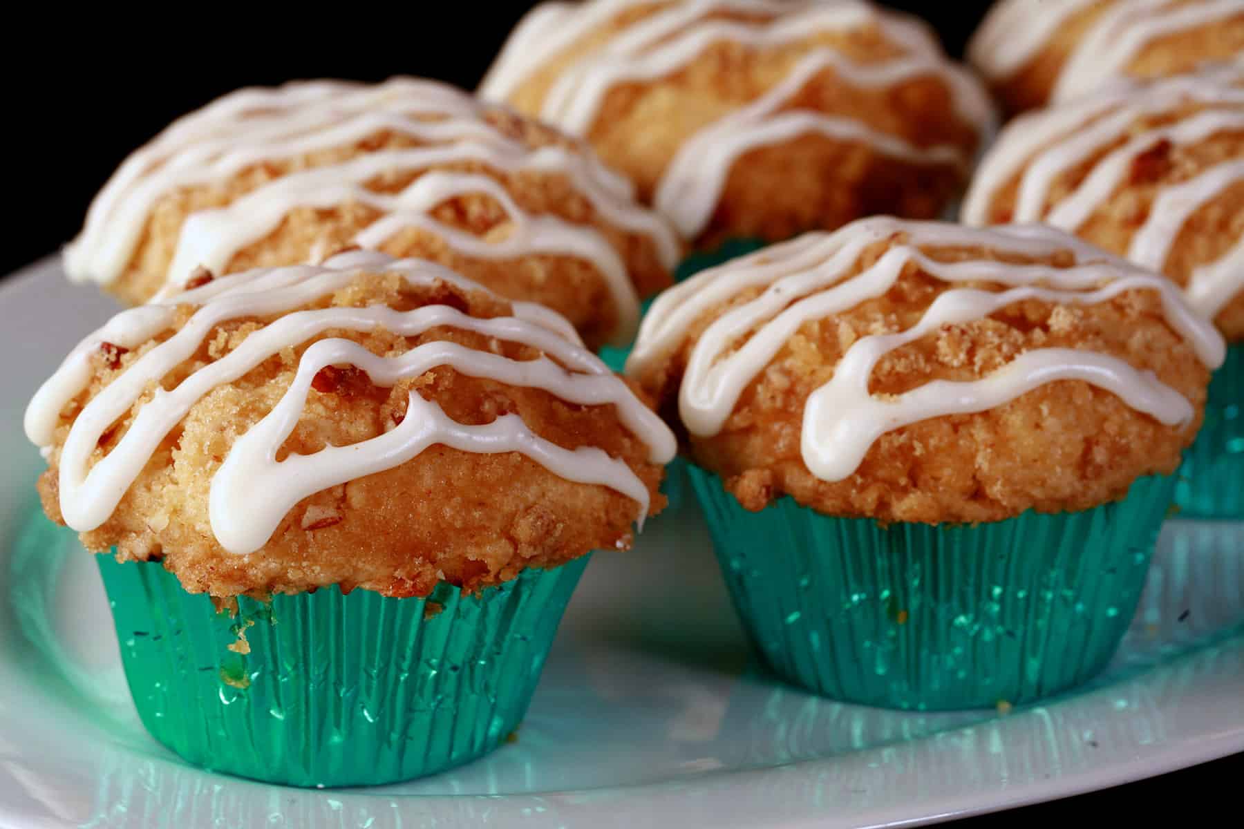 A plate of egg nog muffins, with pecan streusel and drizzled glaze.