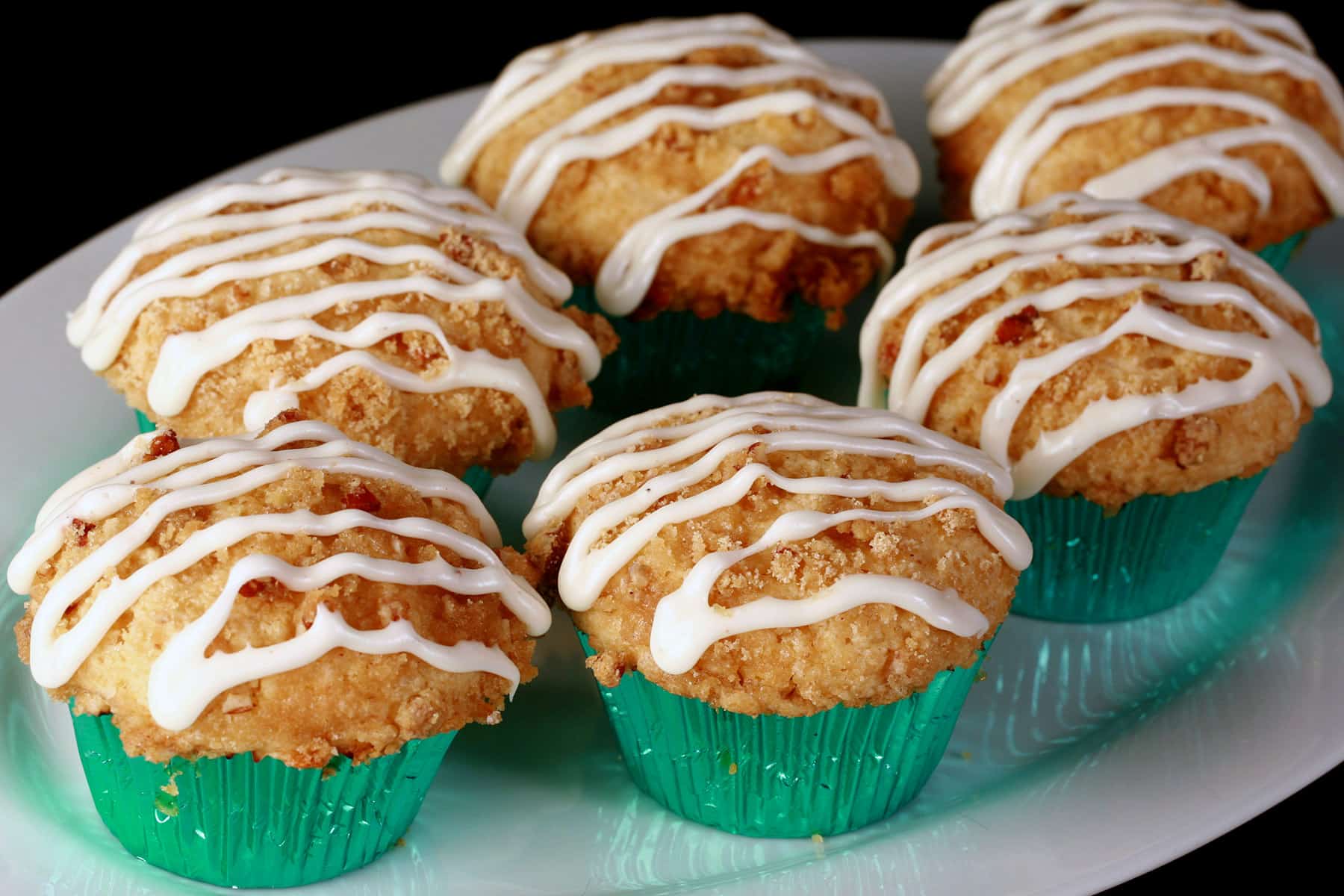A plate of eggnog muffins, with pecan streusel and drizzled glaze.