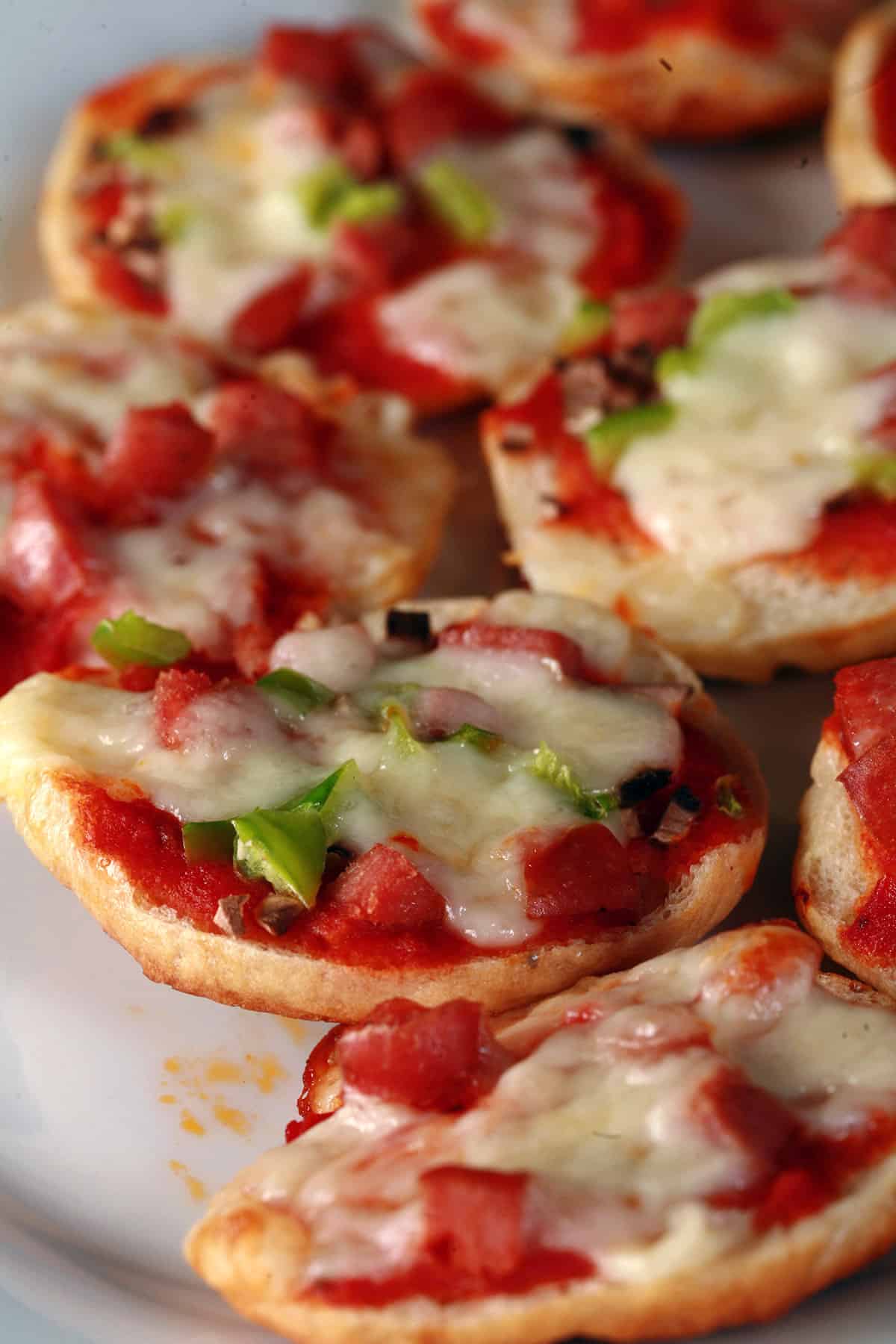 A plate of deluxe homemade bagel bites pizzas, with pepperoni, mushroom, and green peppers.
