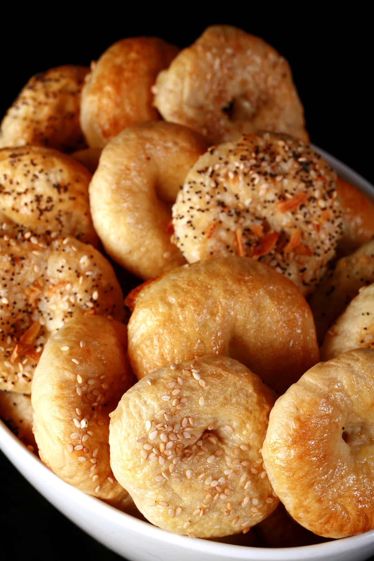 A bowl of mini bagels with various toppings.