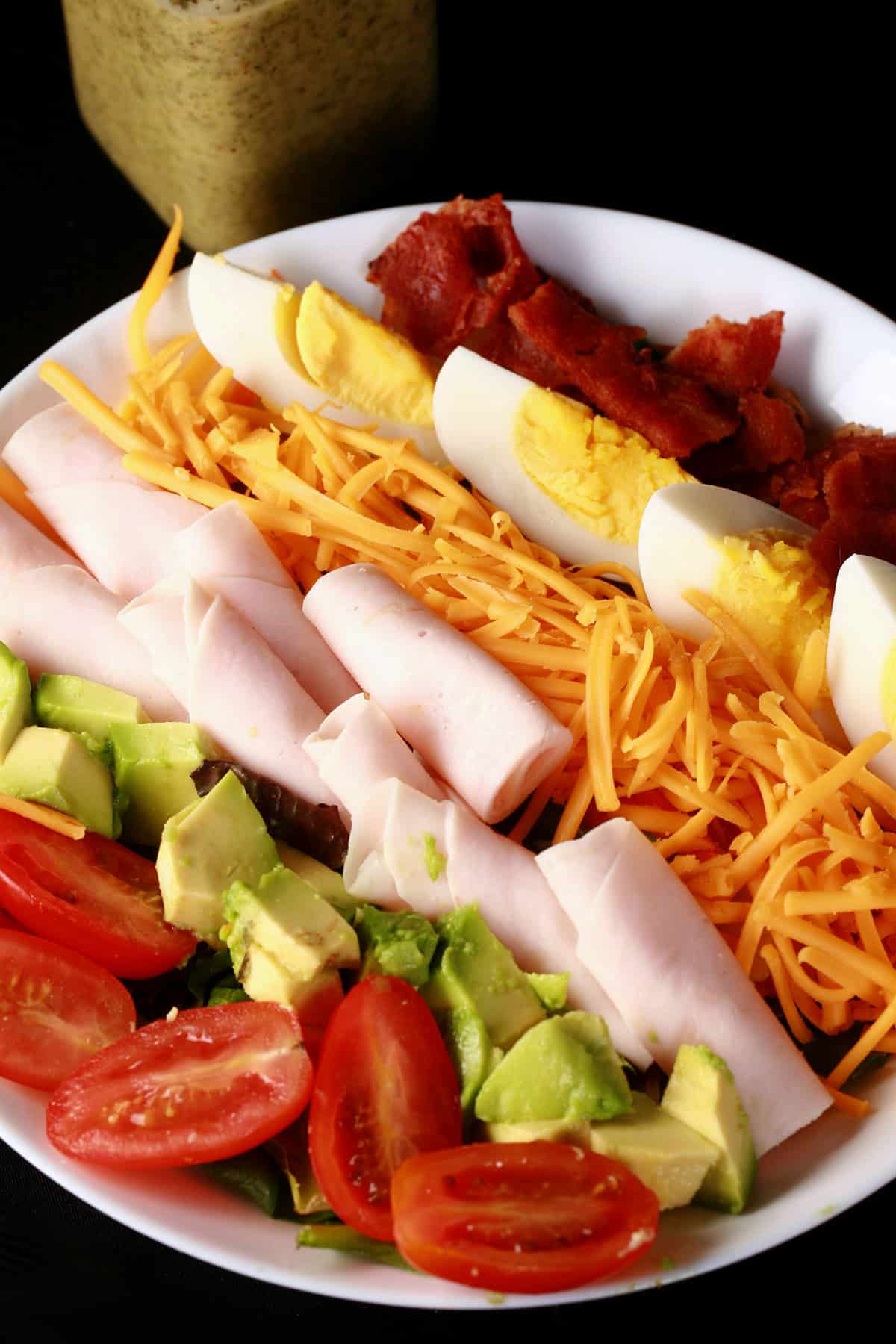 A close up photo of quick cobb salad with rolled deli chicken.