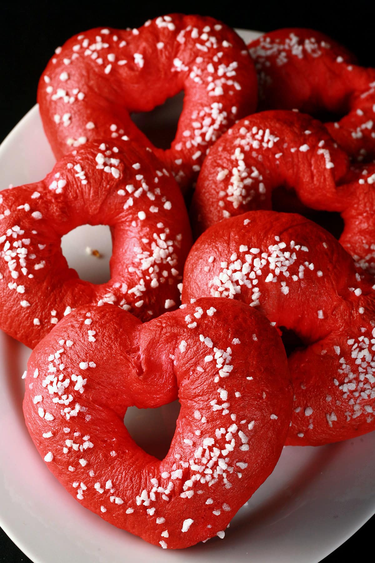 A plate of heart shaped valentines day bagels, topped with coarse sugar.