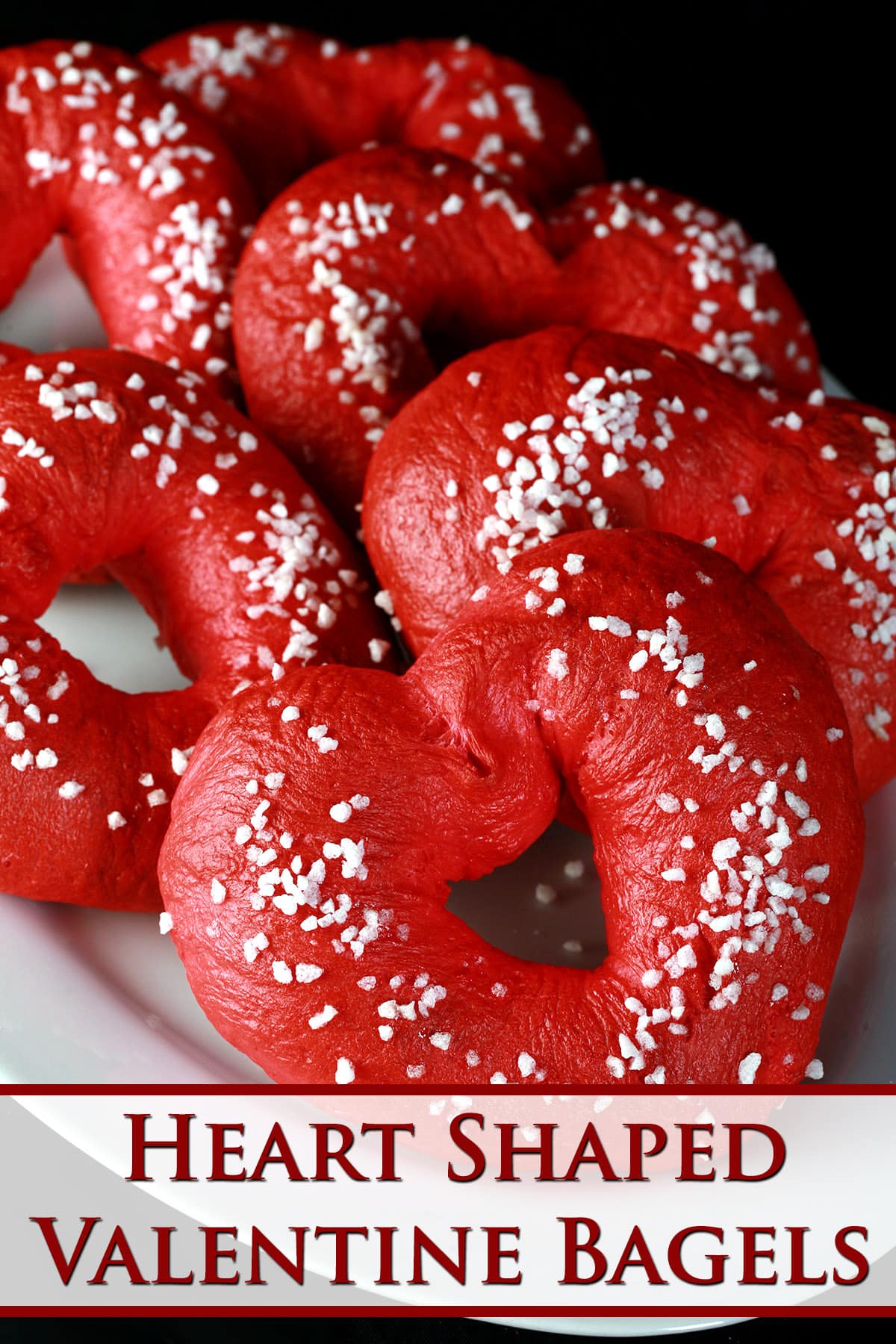 A plate of heart shaped bagels, topped with coarse sugar.