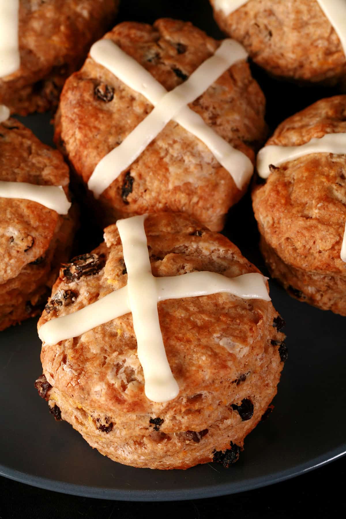 A plate of hot cross scones with orange frosting on top.