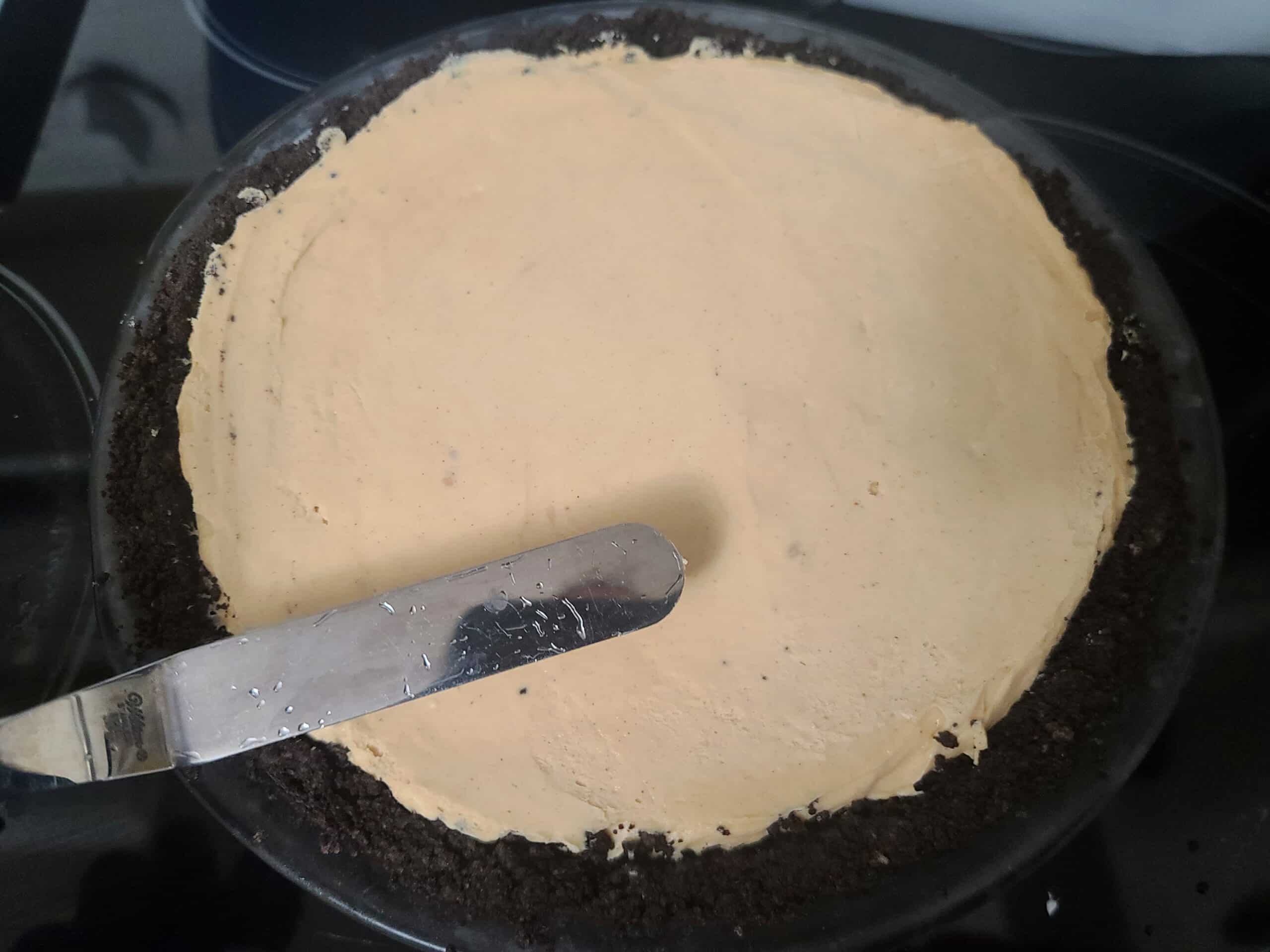 A hot spatula being used to smooth the surface of the peanut butter pie.
