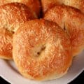 A pile of garlic asiago bagels on a plate.
