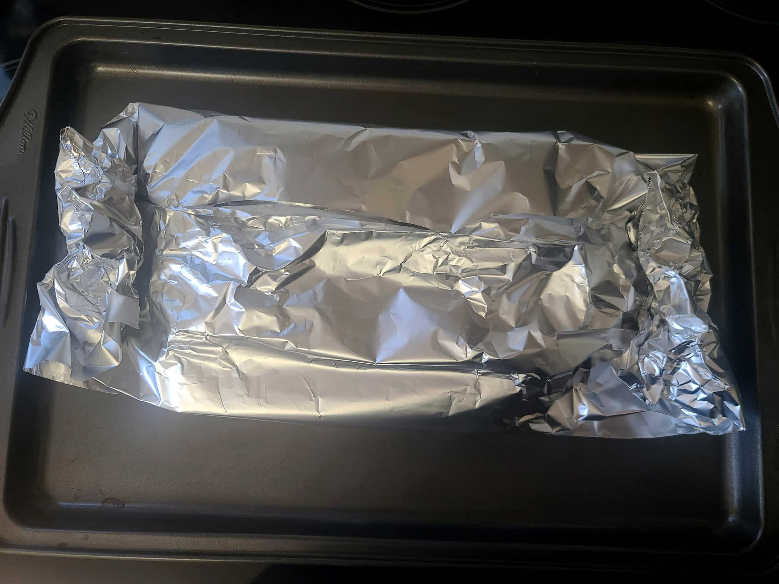 A pan with a foil pouch of garlic on it.