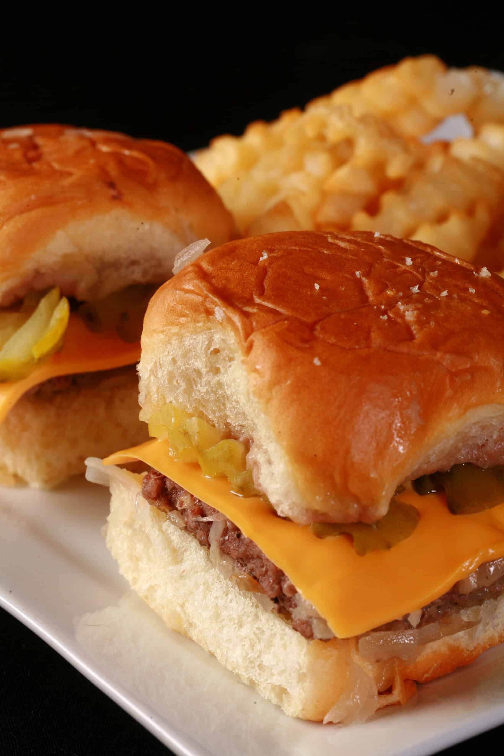 A plate of 3 homemade white castle sliders on a plate with crinkle cut fries.