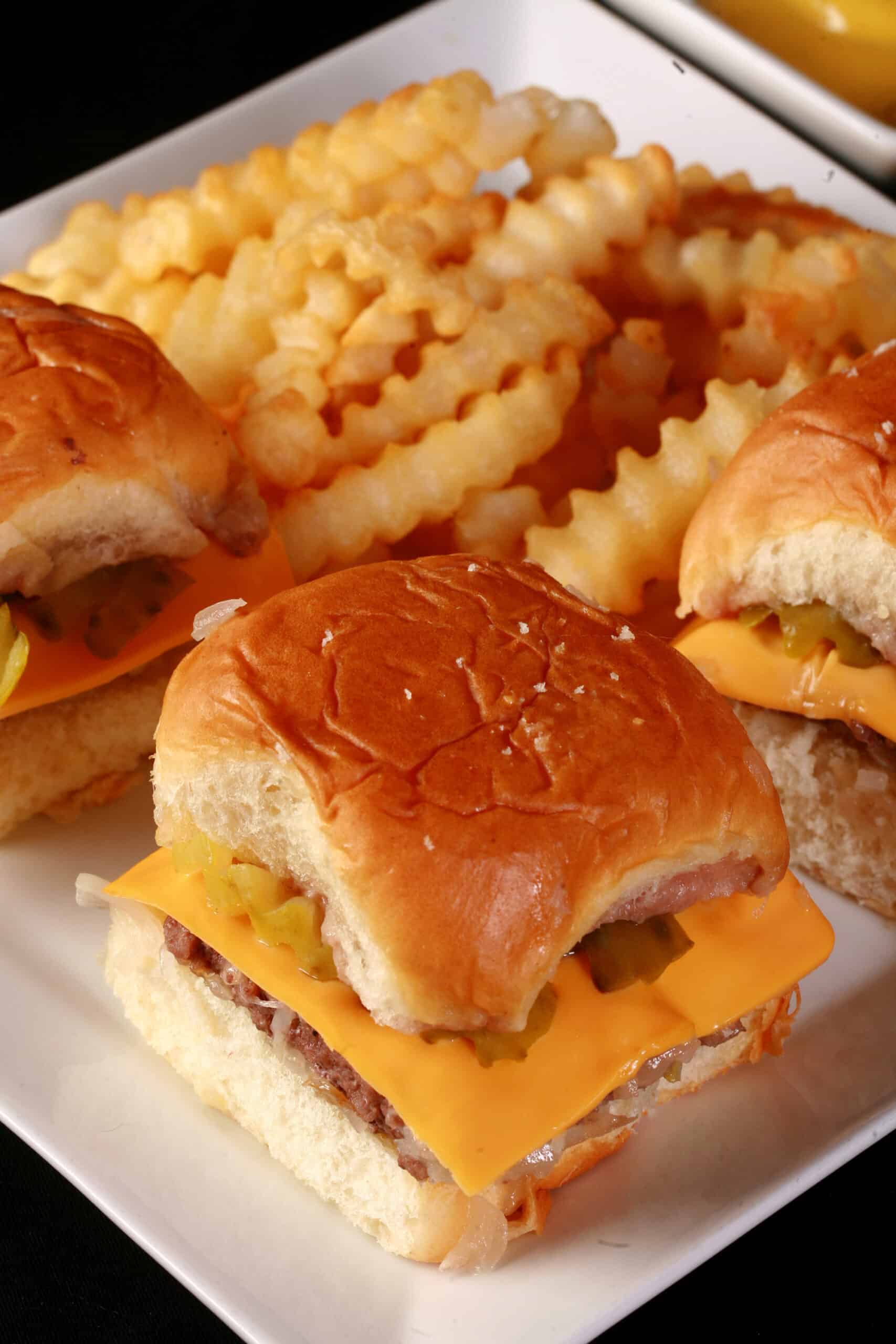 A plate of 3 copycat white castle burgers on a plate with crinkle cut fries.