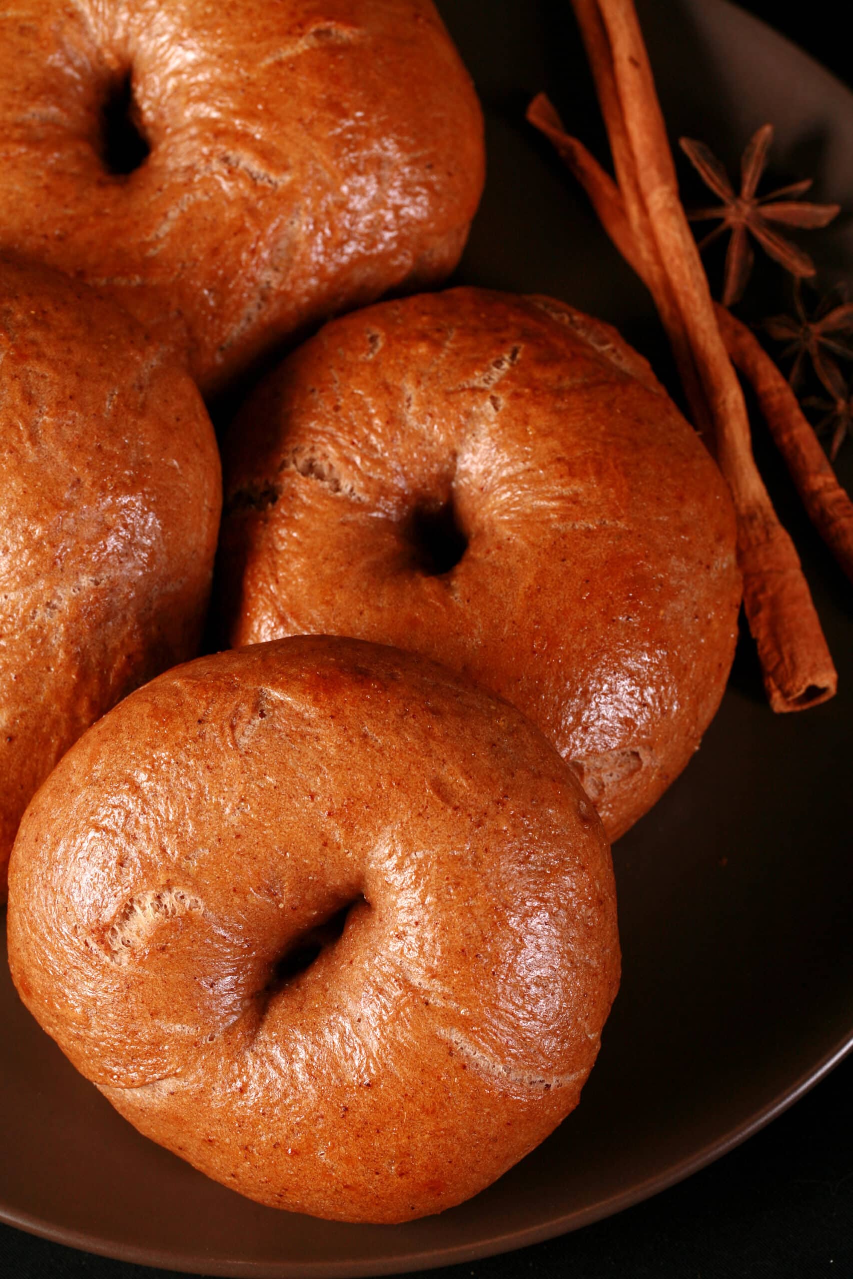 A plate of spiced chai bagels with cinnamon sticks and star anise on the side.