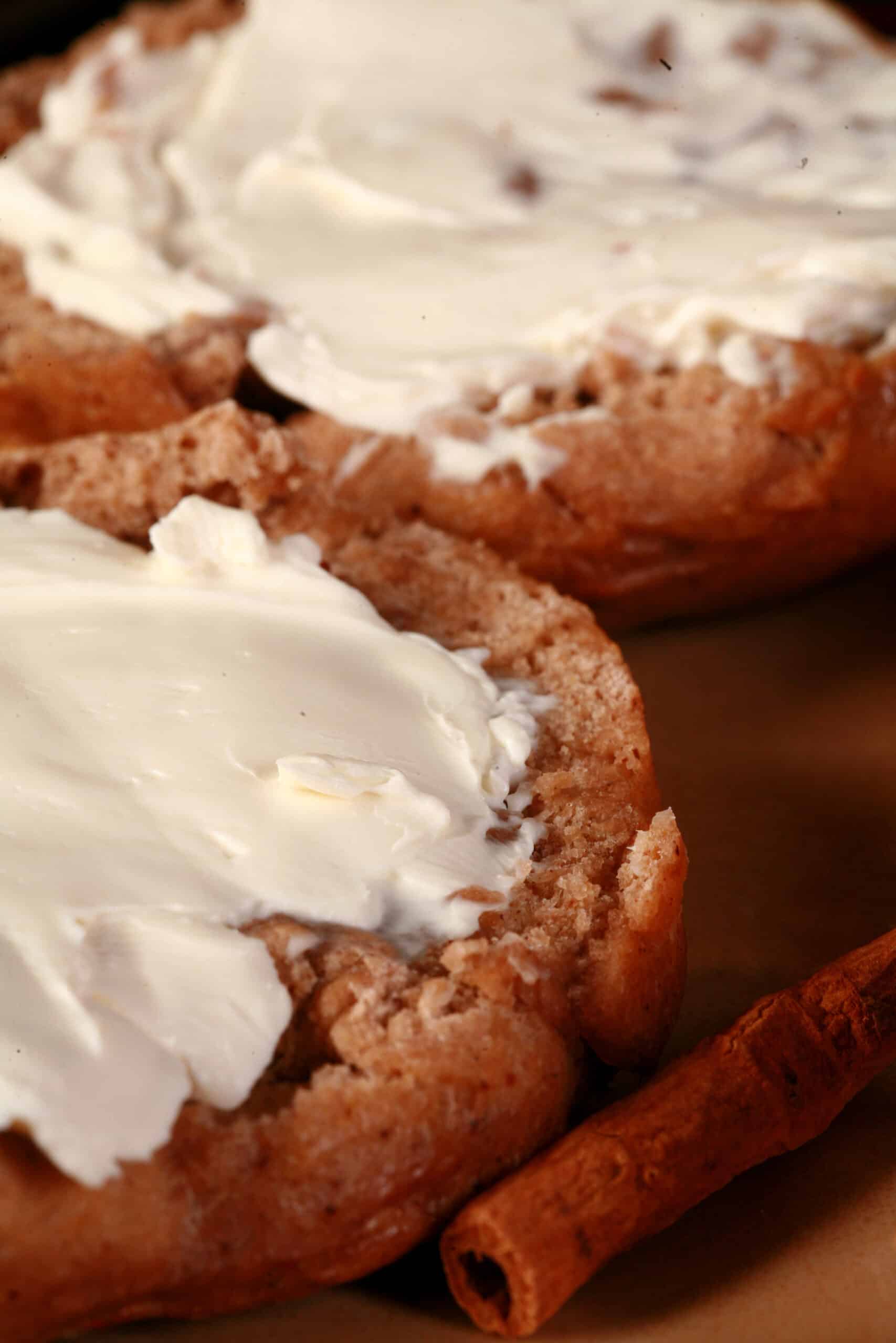 A close up photo of split open chai spice bagel with cream cheese, on a plate.