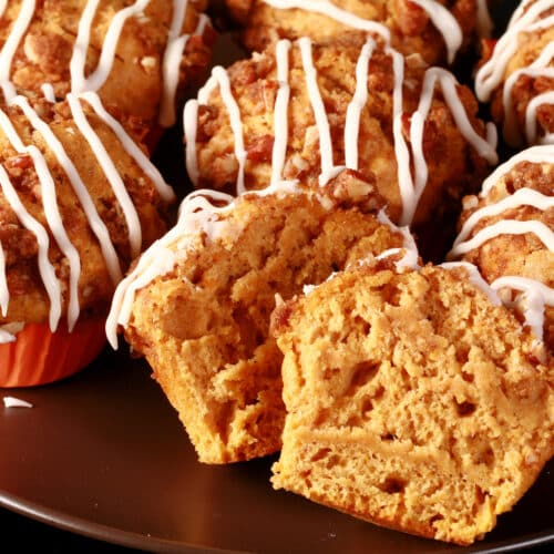 A plate of sweet potato muffins with pecan streusel topping and vanilla glaze drizzled on top.