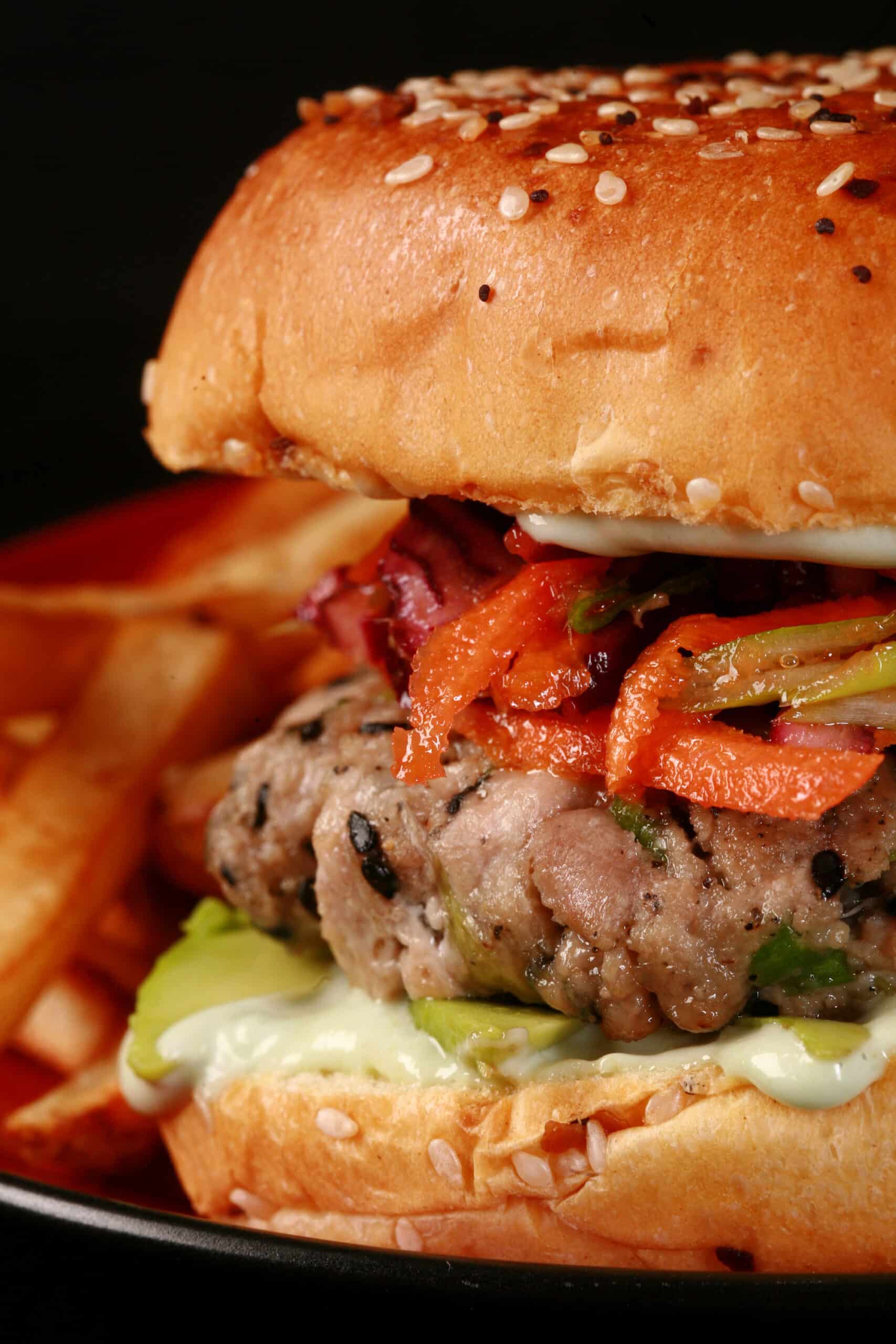 A tuna burger with ginger slaw and wasabi mayo, on a plate with fries.