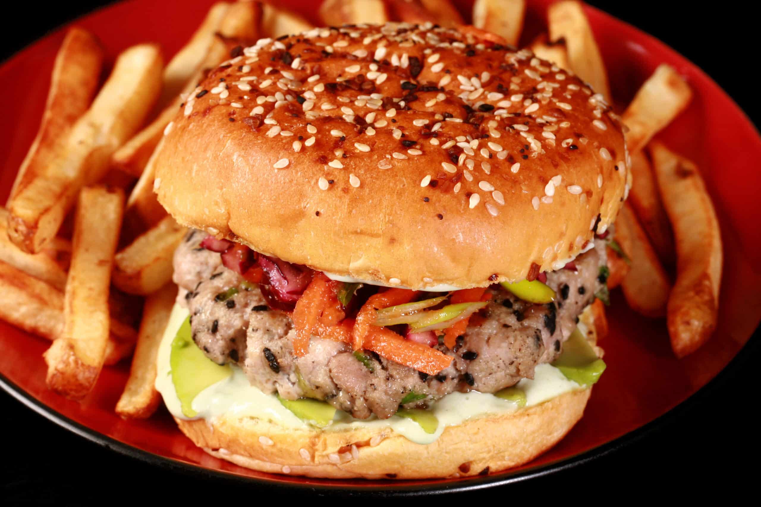 A tuna burger with ginger slaw and wasabi mayo, on a plate with fries.  