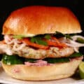 A lemongrass chicken banh mi burger, with cucumbers, pate, cilantro, jalapenos, and pickled root veggies.