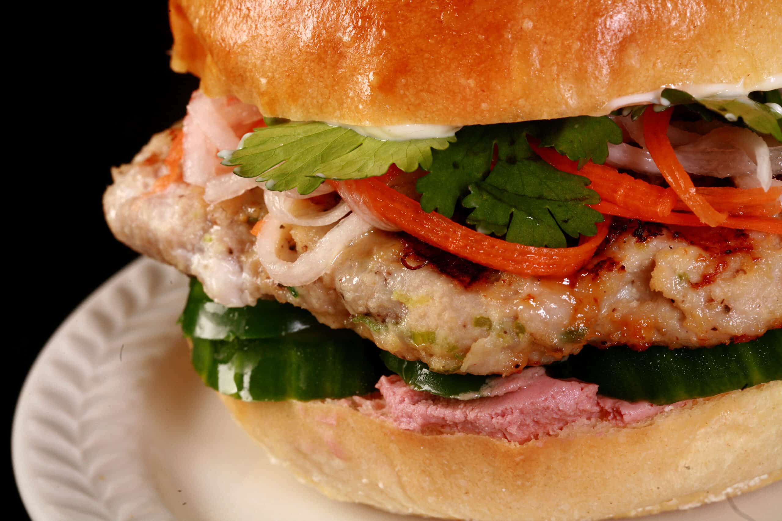 A close up view of a lemongrass chicken banh mi burger.