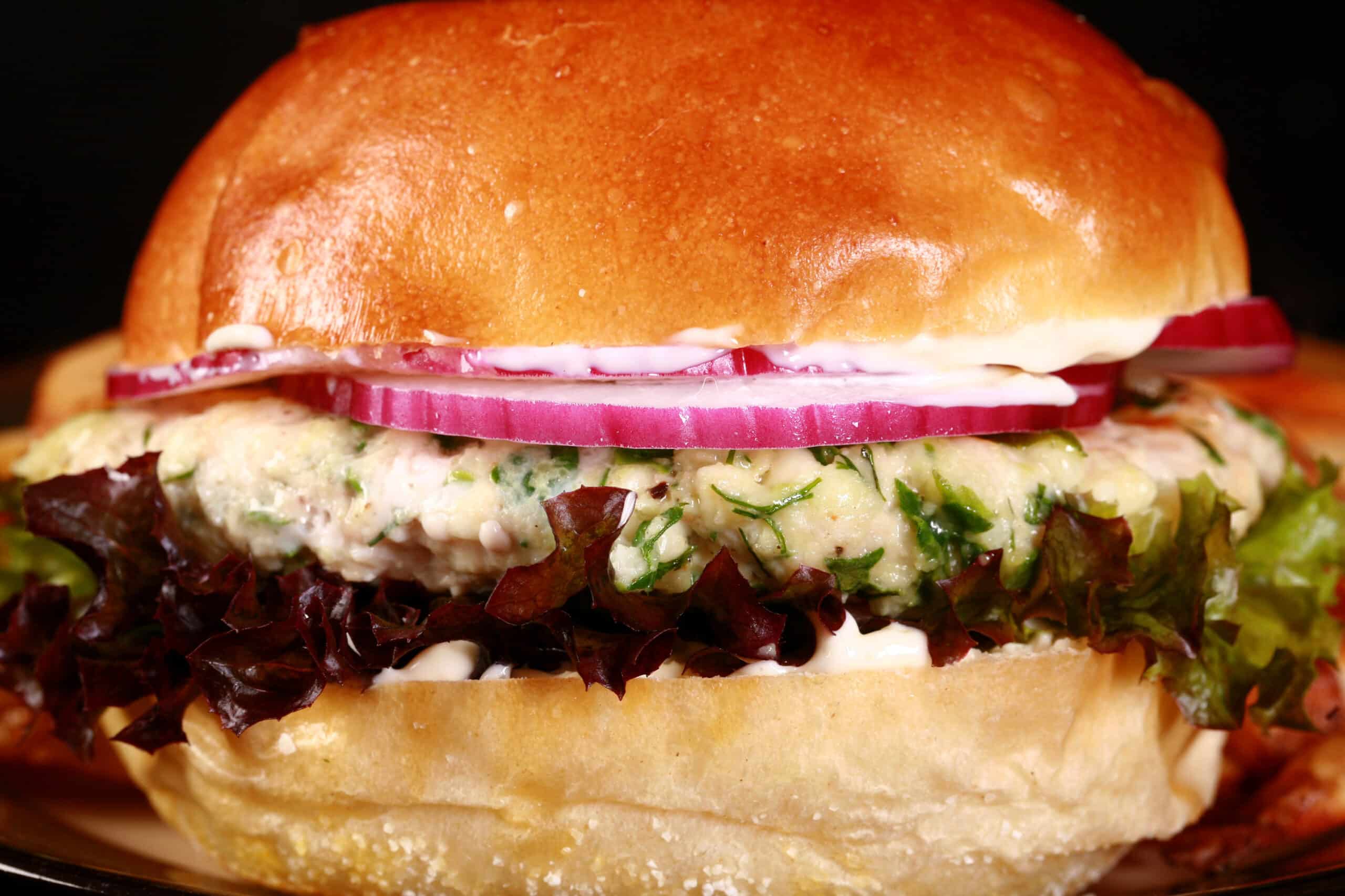 A Mediterranean chicken burger. The chicken patty is flecked with spinach and feta, there are fries behind it.