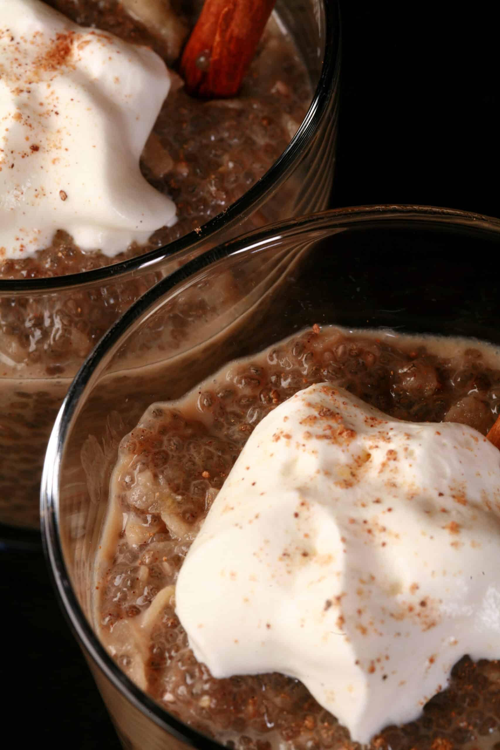 2 glasses of apple chia seed pudding, topped with whipped cream and nutmeg.