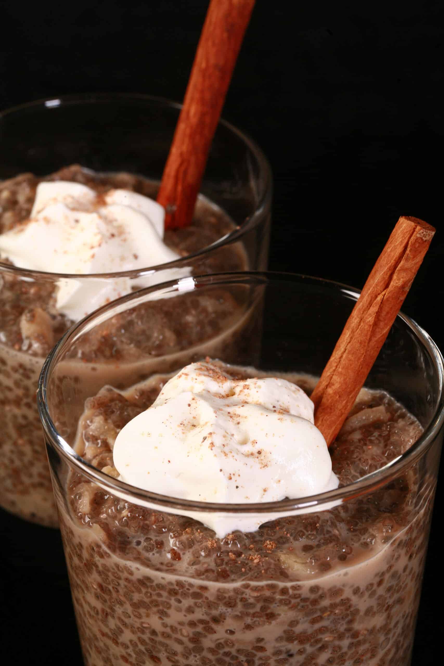 2 glasses of apple chia pudding, topped with whipped cream and nutmeg.