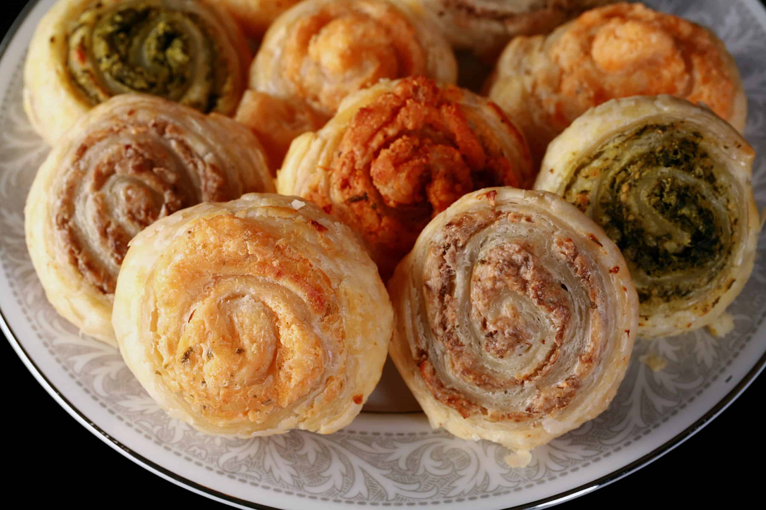 Mushroom, Spinach, Onion, and sun dried tomato spiral puff pastry pinwheels on a plate.