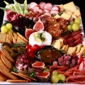 A festive christmas charcuterie platter with meats, cheeses, fruit and crackers in a variety of textures and jewel tone colours.
