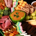 An Irish themed Charcuterie board with Irish cheeses, Guiness Cheese Dip, Gold chocolate coins, rainbow candy, and more.