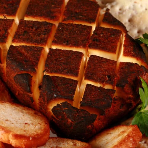 A brick of dry rub smoked cream cheese, surrounded by various crackers.