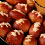 A plate of mini football pretzel bites, with a bowl of hot cheese dip.