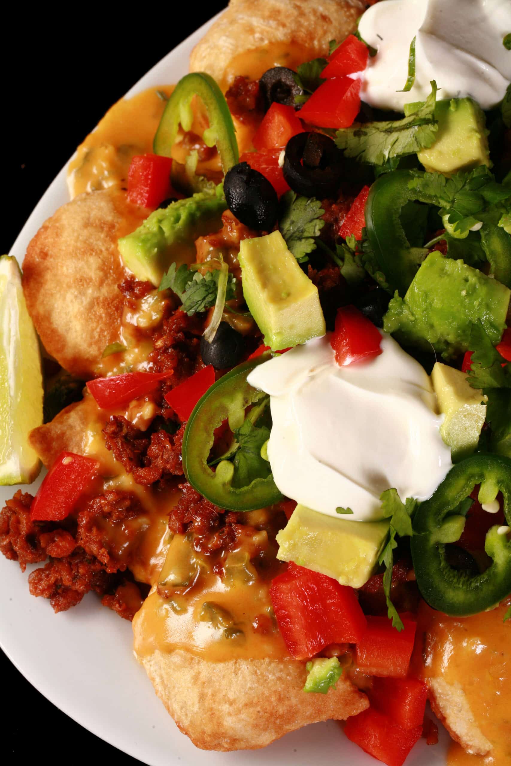 A plate of loaded perogy nachos - deep fried pierogi topped with jalapeno cheese sauce, nacho meat, and other toppings.