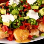 A plate of loaded perogy nachos - deep fried pierogi topped with jalapeno cheese sauce, nacho meat, and other toppings.