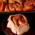 A pan of peanut butter and jelly rolls, with one on a plate in front.