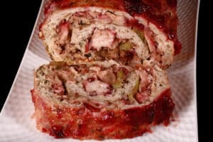 A rolled turkey thanksgiving meatloaf, with stuffing and cranberry sauce.