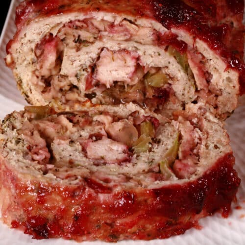 A rolled turkey thanksgiving meatloaf, with stuffing and cranberry sauce.