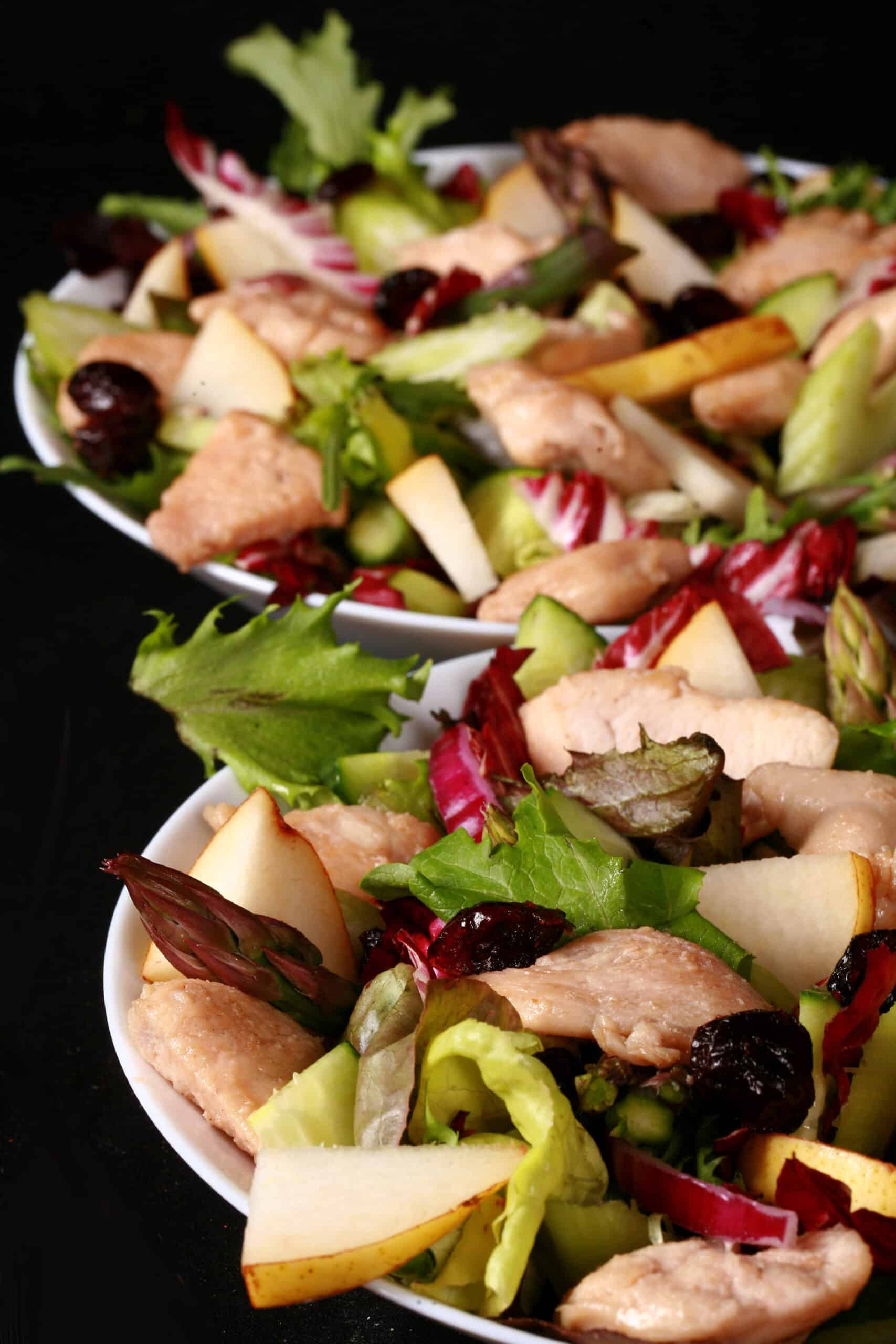 2 bowls of balsamic chicken salad with cranberries and pears, as well as a bottle of cranberry-pear white balsamic vinaigrette.