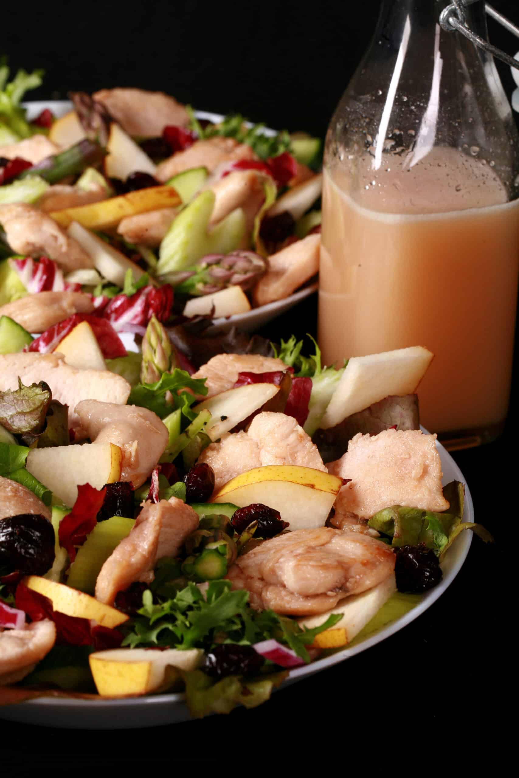 2 bowls of balsamic chicken salad with cranberries and pears, as well as a bottle of cranberry-pear white balsamic vinaigrette.