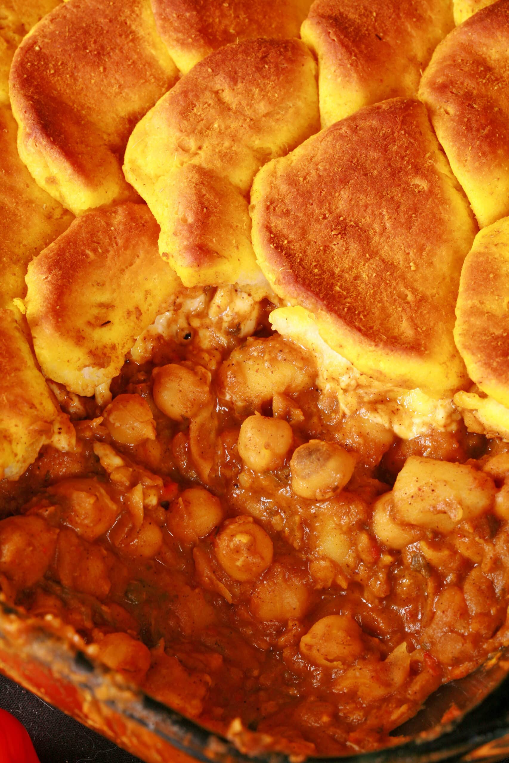 A serving of doubles hotdish - a trinidadian inspired casserole with a spiced chickpea and potato filling, topped with spiced butter brushed biscuits.