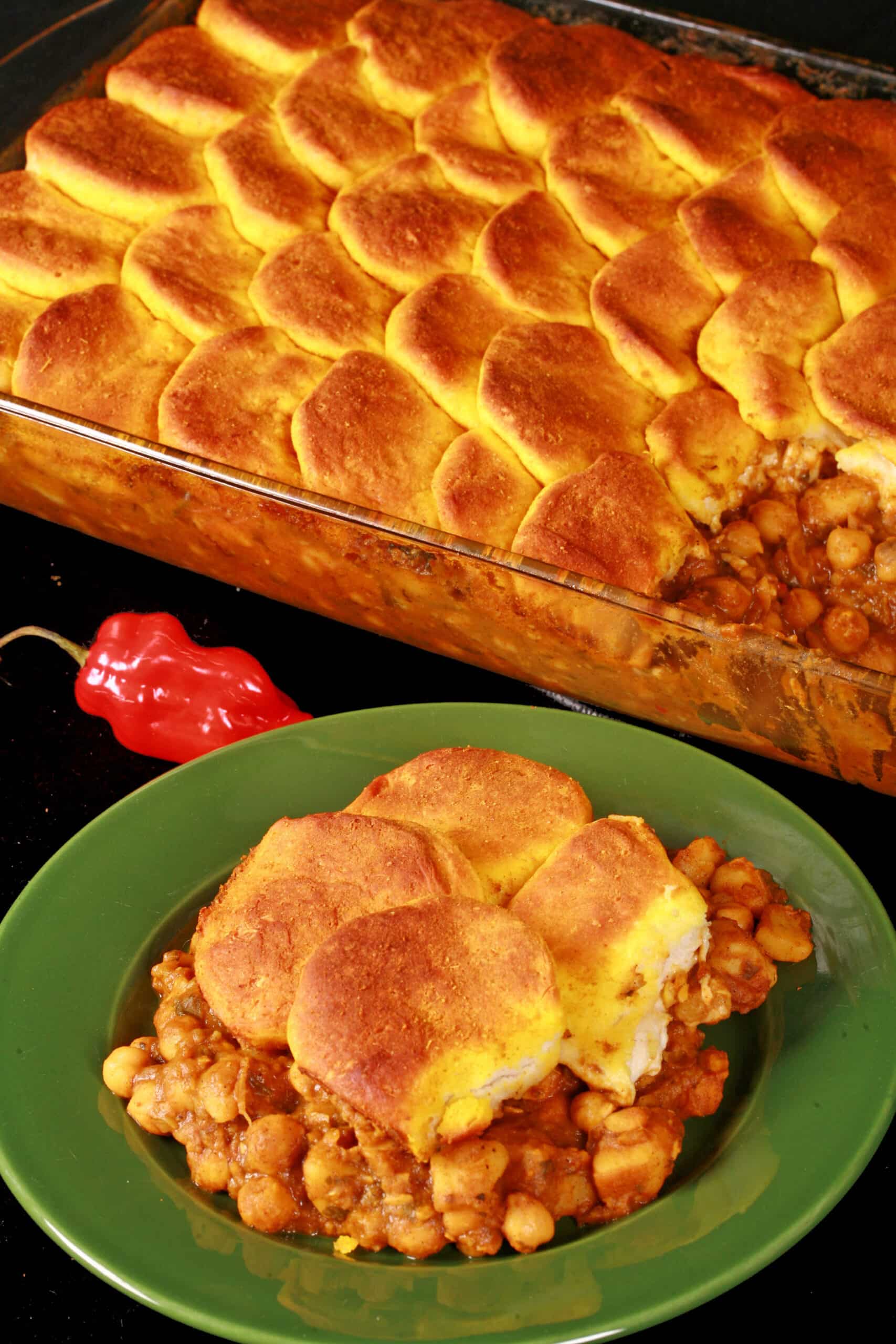 A serving of doubles casserole - a carribean inspired hotdish with a spiced chickpea and potato filling, topped with spiced butter brushed biscuits.