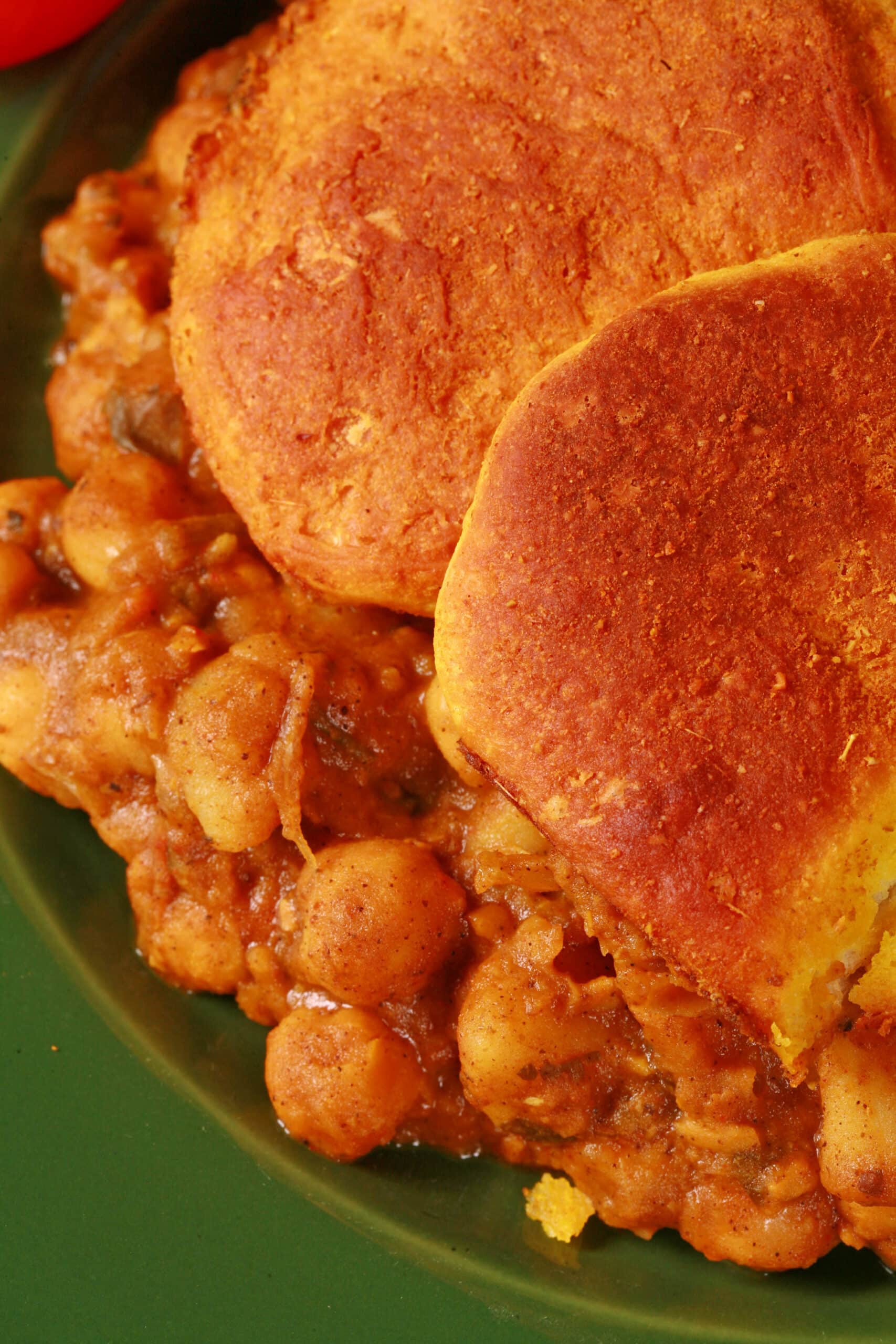 A serving of doubles hotdish - a trinidadian inspired casserole with a spiced chickpea and potato filling, topped with spiced butter brushed biscuits.