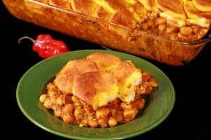 A serving of doubles hotdish - a trinidadian inspired casserole with a spiced chickpea and potato filling, topped with spiced butter brushed biscuits.