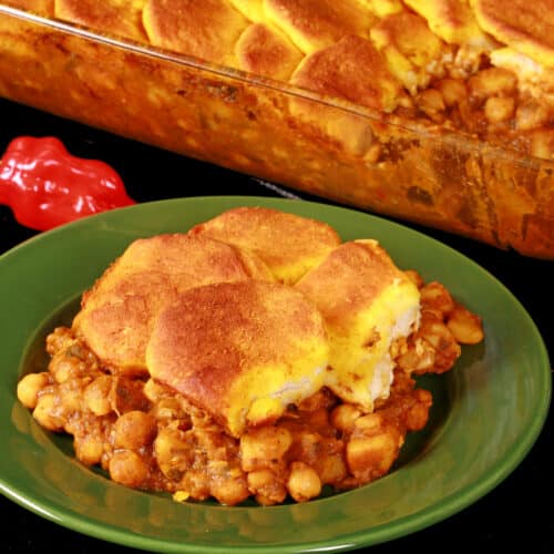 A serving of doubles hotdish - a trinidadian inspired casserole with a spiced chickpea and potato filling, topped with spiced butter brushed biscuits.