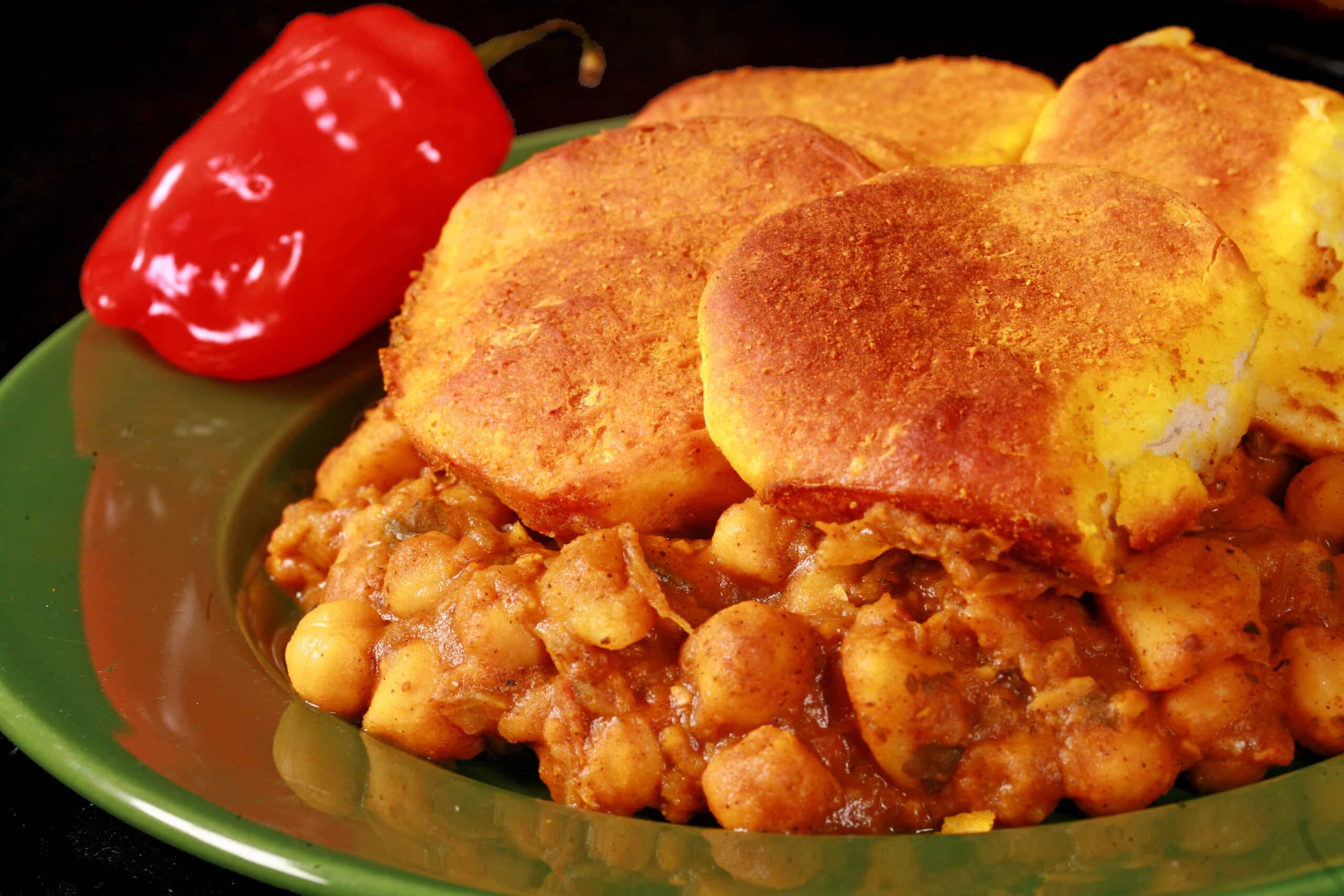 A serving of doubles casserole - a carribean inspired hotdish with a spiced chickpea and potato filling, topped with spiced butter brushed biscuits.