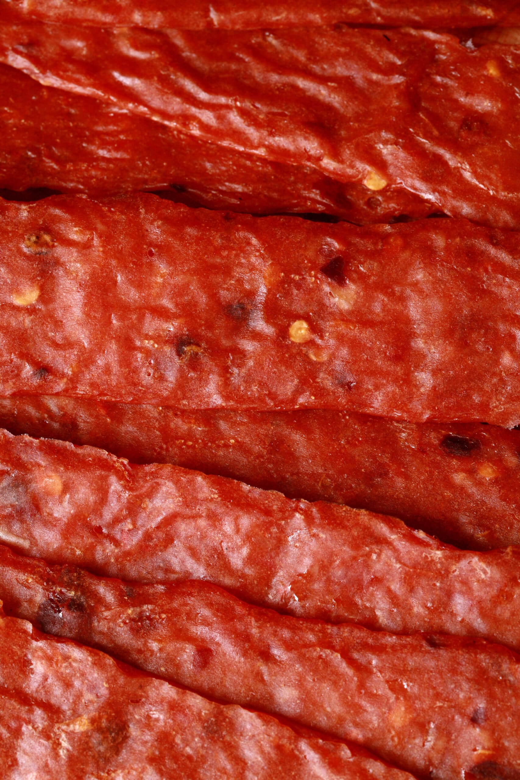 Several strips of spicy orange chicken jerky on a cutting board.