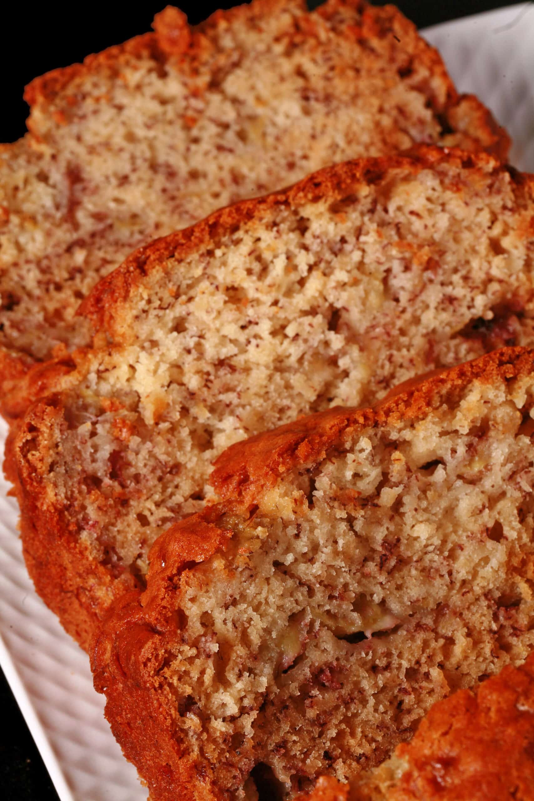 A sliced loaf of no egg banana bread on a white serving platter.