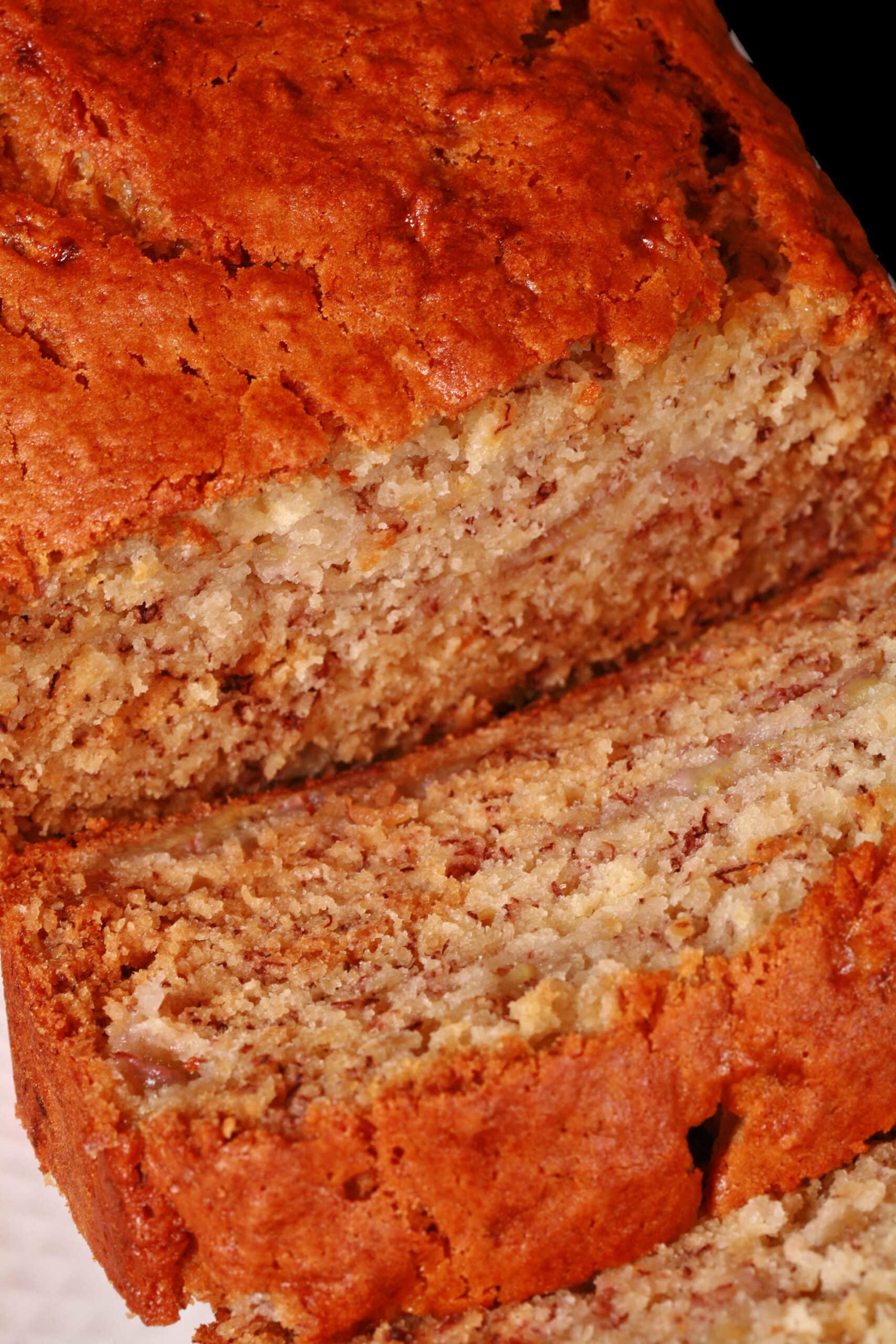 A sliced loaf of eggless banana bread on a white serving platter.