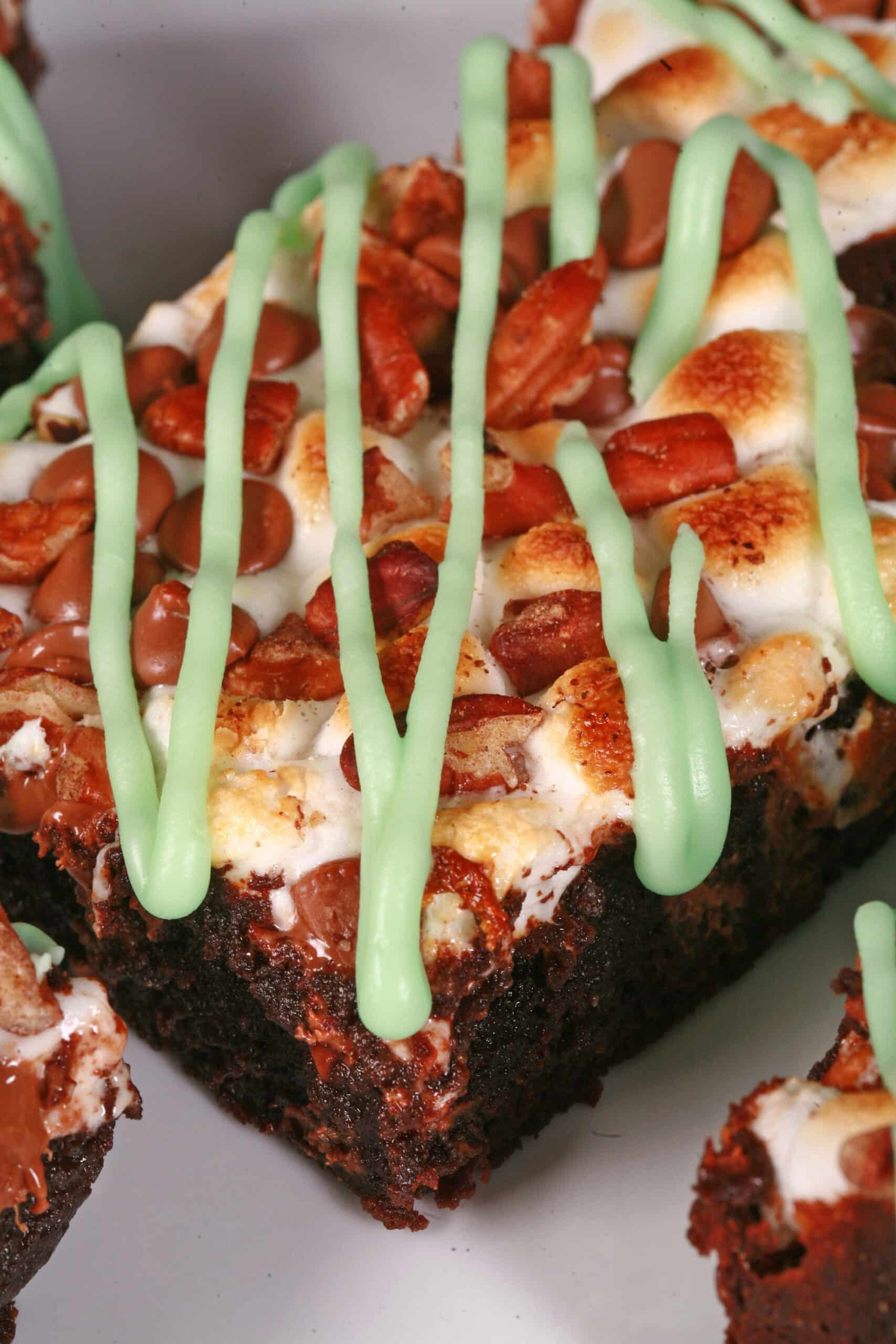 A plate of St Patrick’s Day brownies topped with toasted marshmallows, pecans, chocolate chips, and green tinted icing.