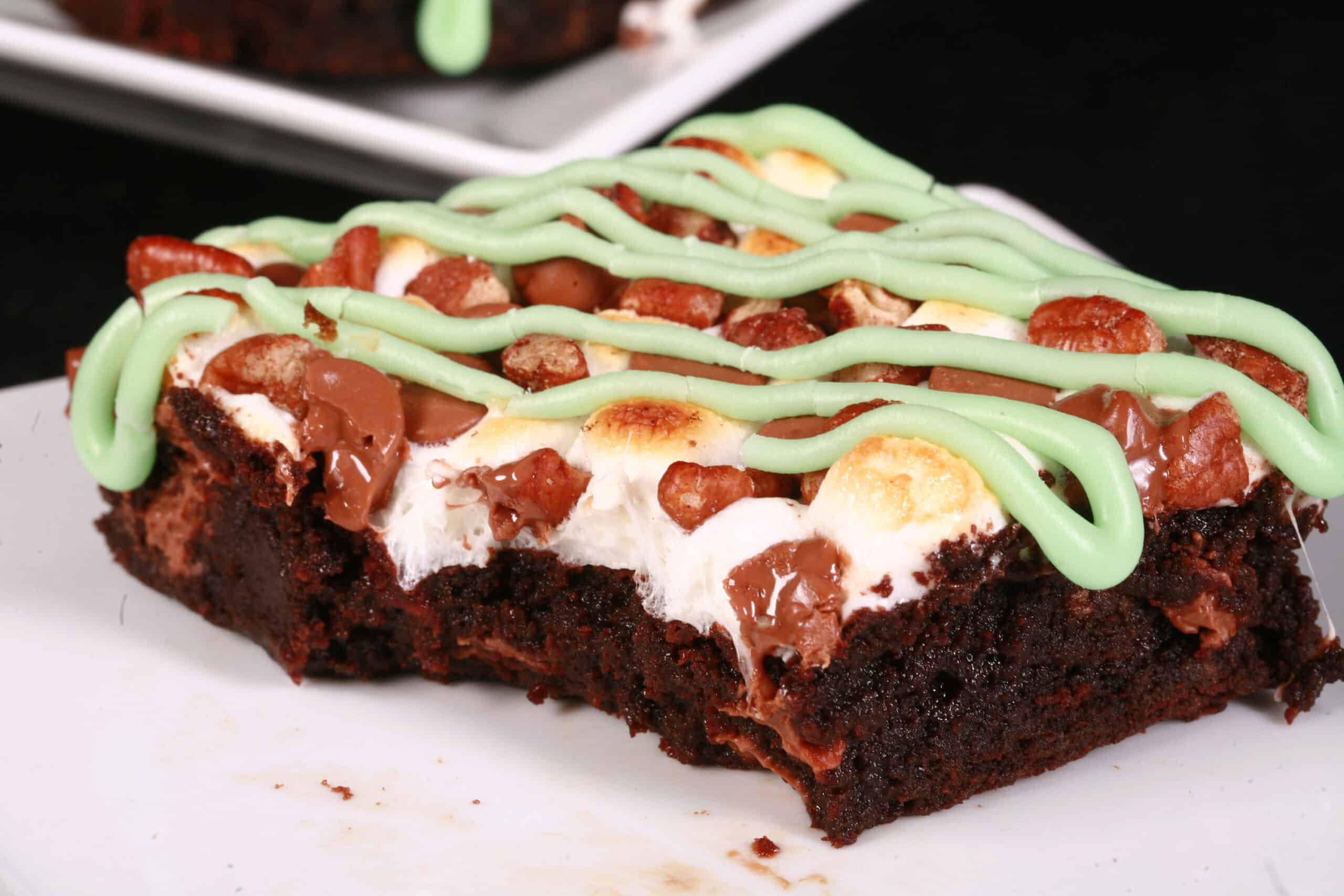 A plate of St Patrick’s Day brownies topped with toasted marshmallows, pecans, chocolate chips, and green tinted icing.