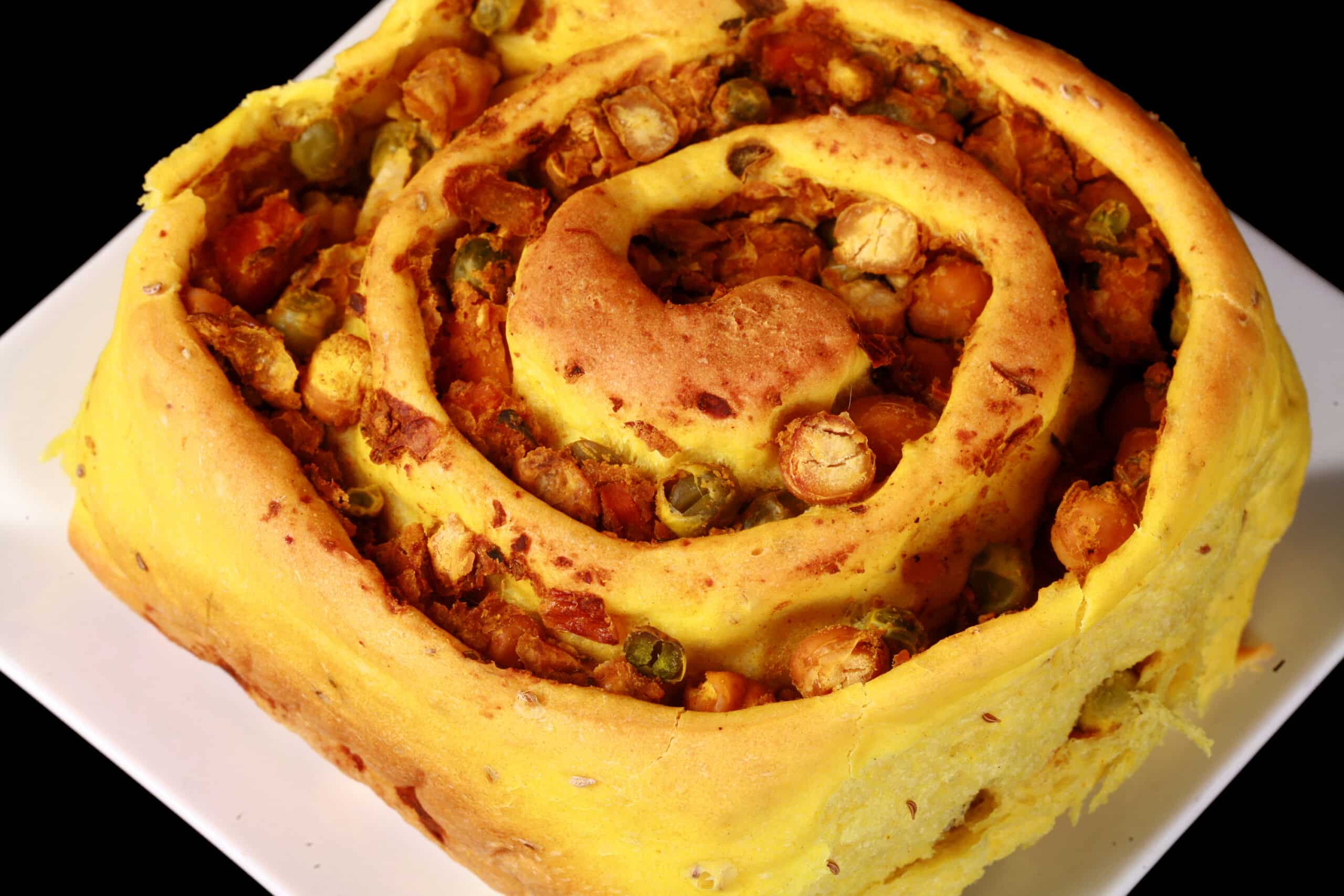 A Samosa Roll - A spiced dough rolled around a chickpea samosa filling, cinnamon roll style.