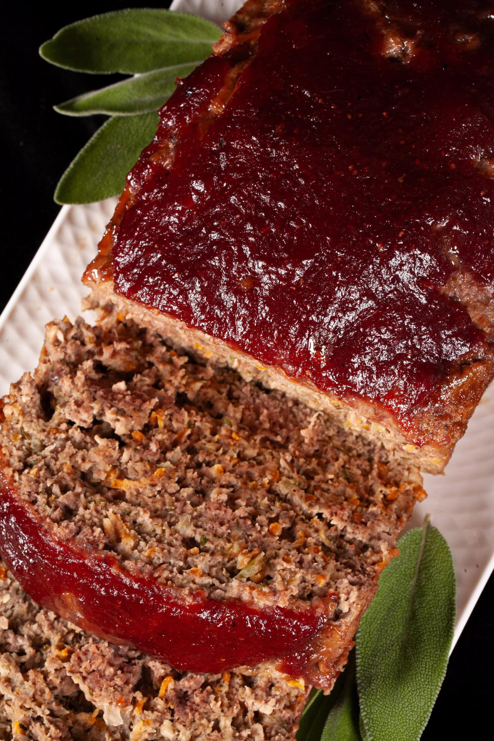 Deer meatloaf with carrots, mushrooms, celery bits, and herbs visible, topped with cranberry glaze.