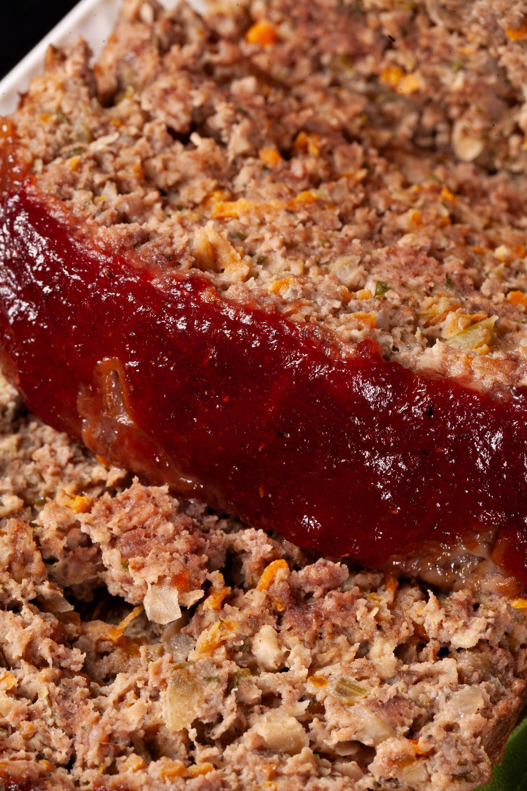 Deer meatloaf with carrots, mushrooms, celery bits, and herbs visible, topped with cranberry glaze.
