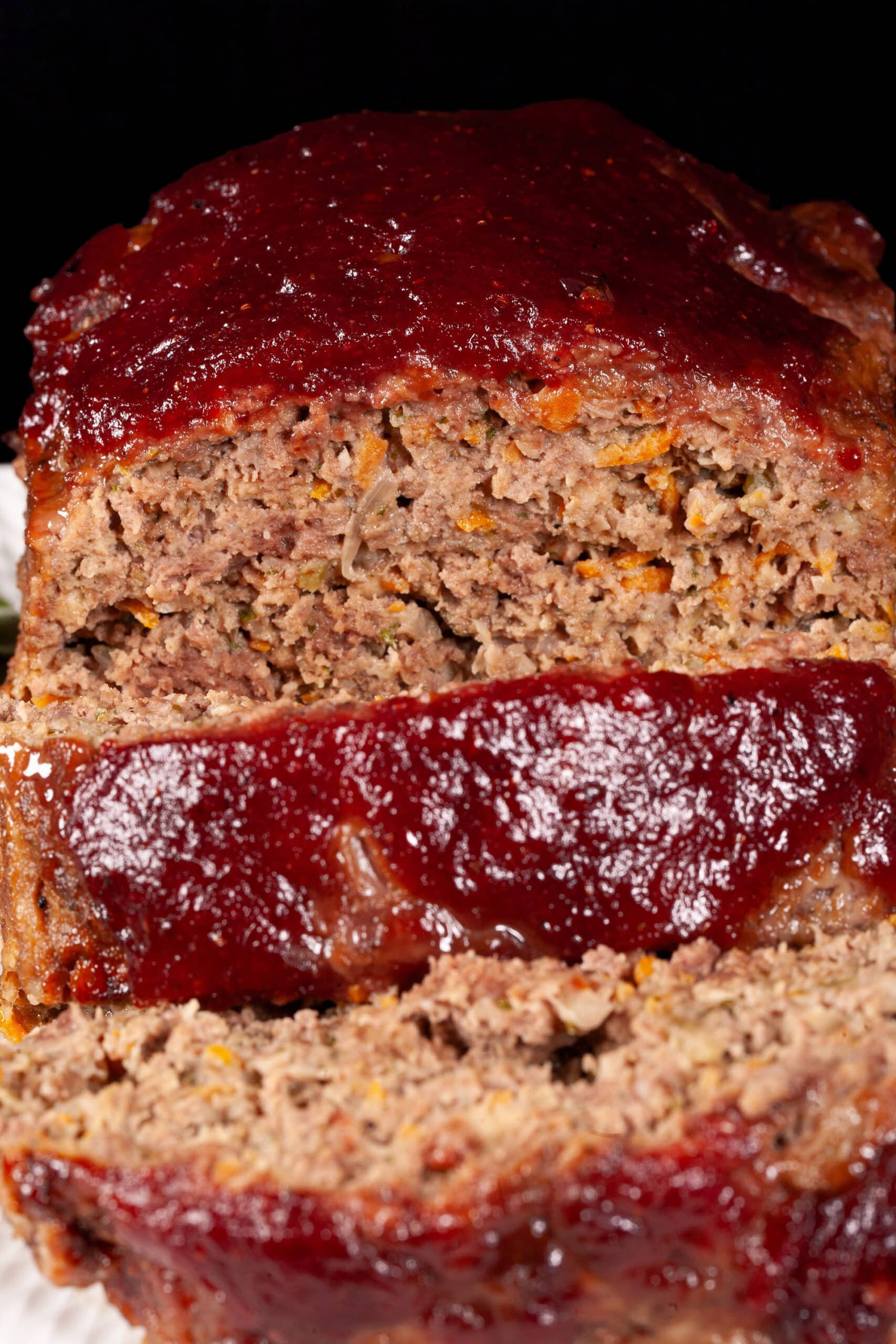 Deer meatloaf with carrots, mushrooms, celery bits, and herbs visible, topped with cranberry glaze.